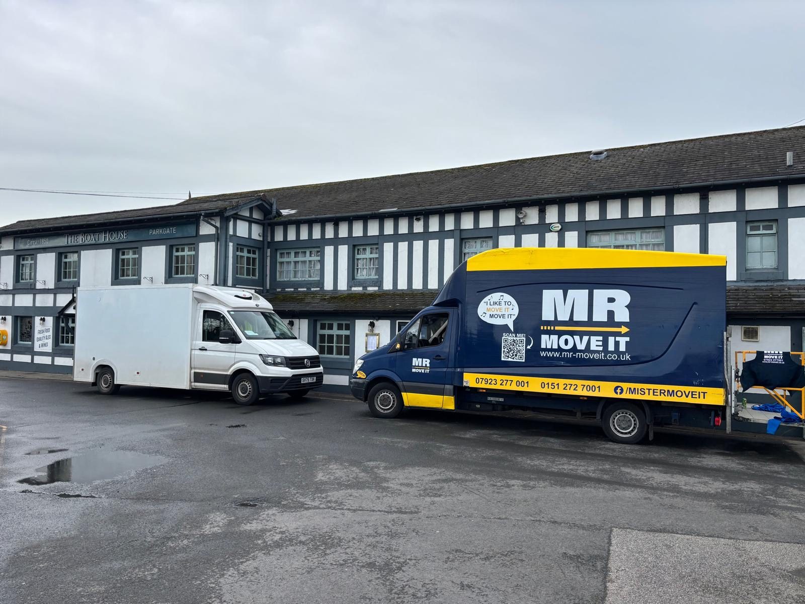Mr Move It Luton van parked beside a white box van outside a black-and-white Tudor-style building