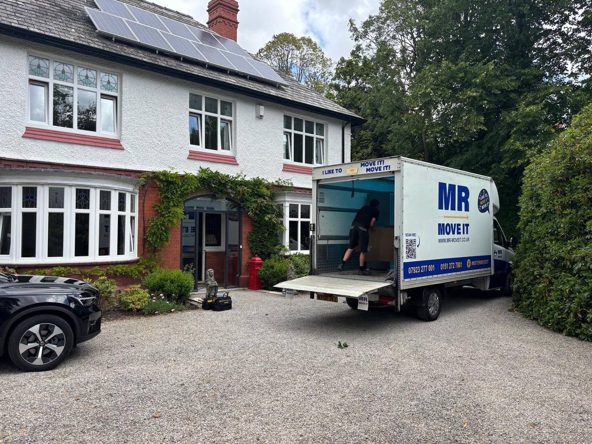 Mr Move It removals van with tail-lift down, loading outside a detached house